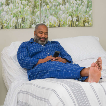 Man using a phone while relaxing in a Transfer Master Supernal 5 Hi-Low Adjustable Bed, demonstrating homecare comfort.